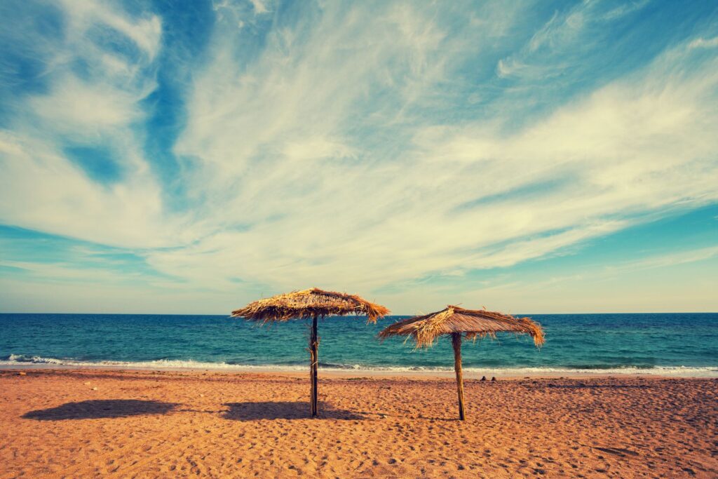 sunny hot day on the beach with 2 beach umbrellas