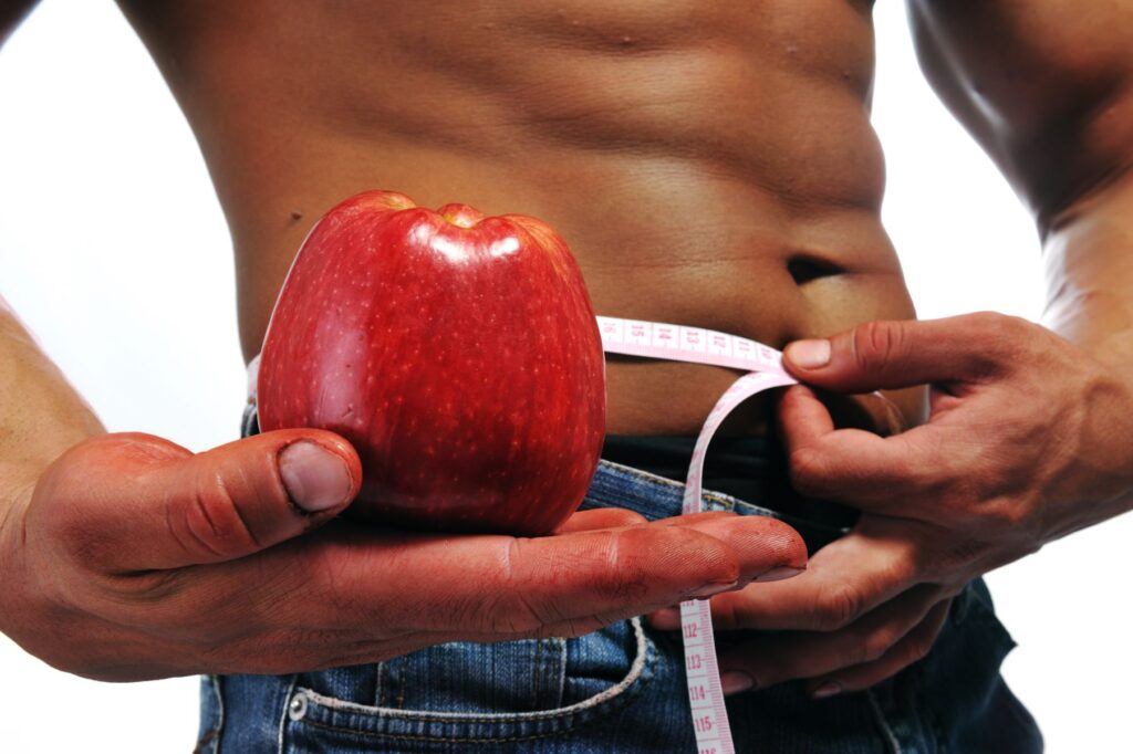 man with measuring tape and an apple trying to measure his waist