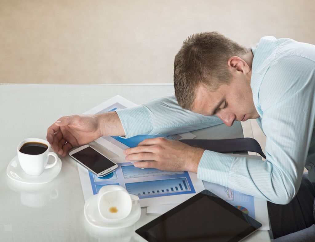 tired and sleepy man falling asleep at the desk at work